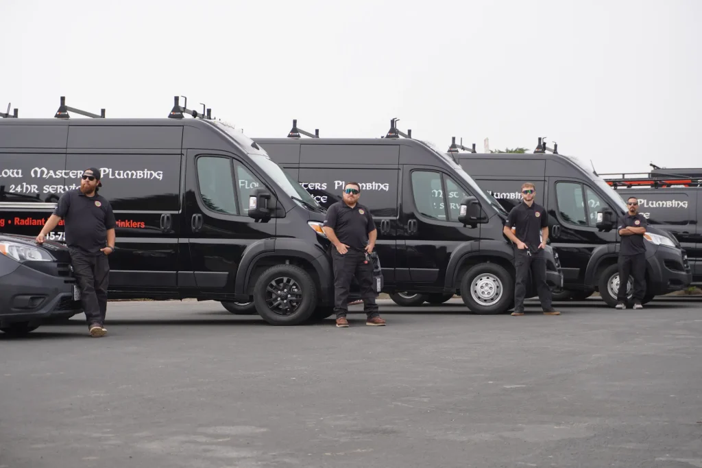Plumbers in Daly City beside their service vans.