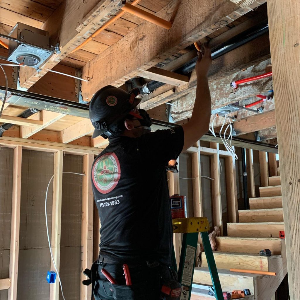 Plumber in Redwood City fitting pipes in a residential property under construction.