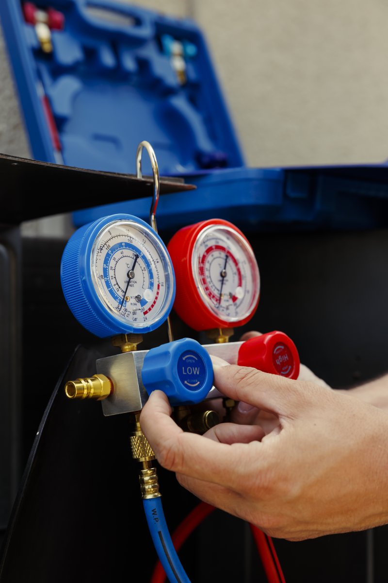 Technician checking AC refrigerant pressure gauges.