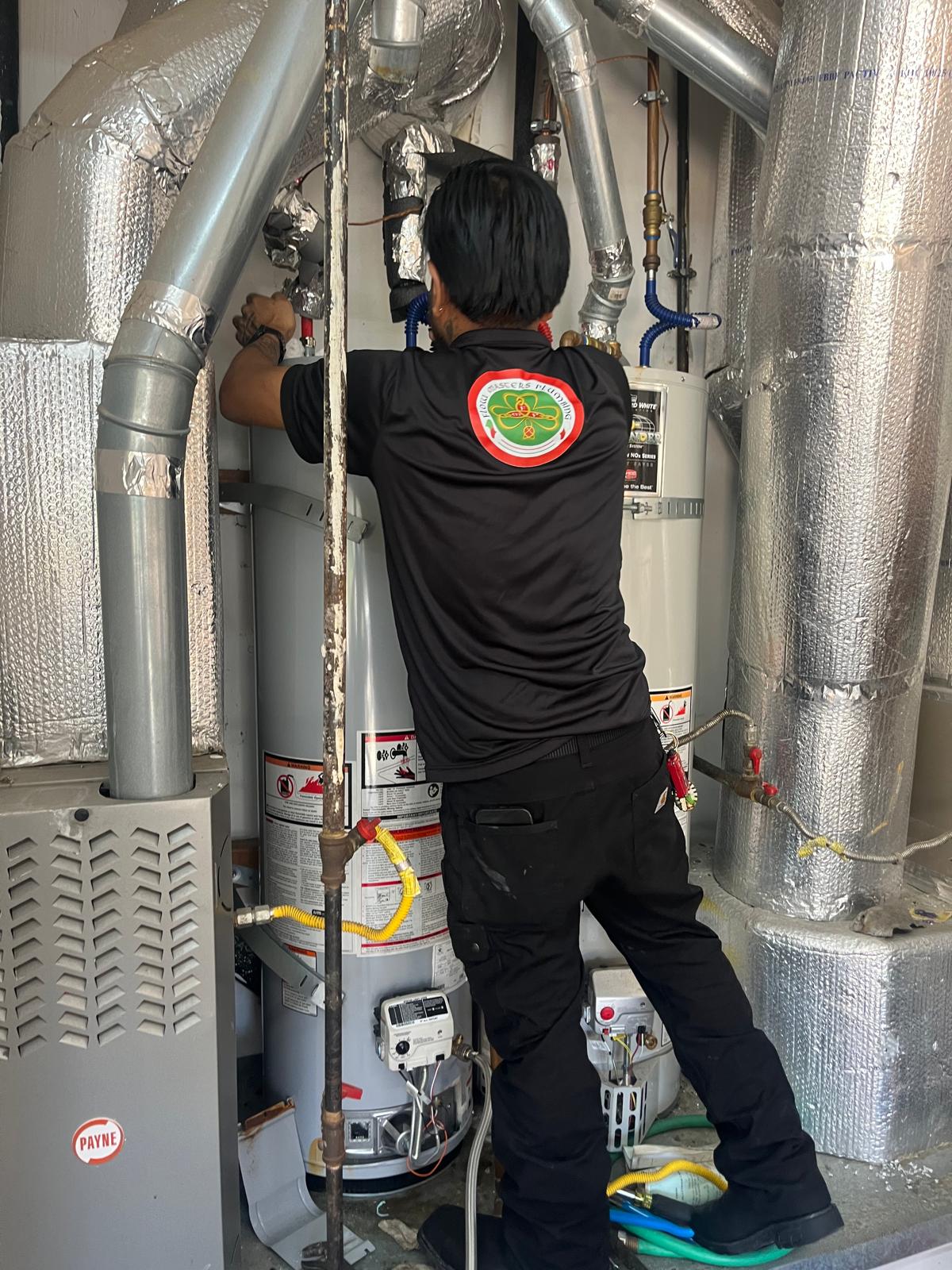 Flow Masters technician beside a furnace and water heater.